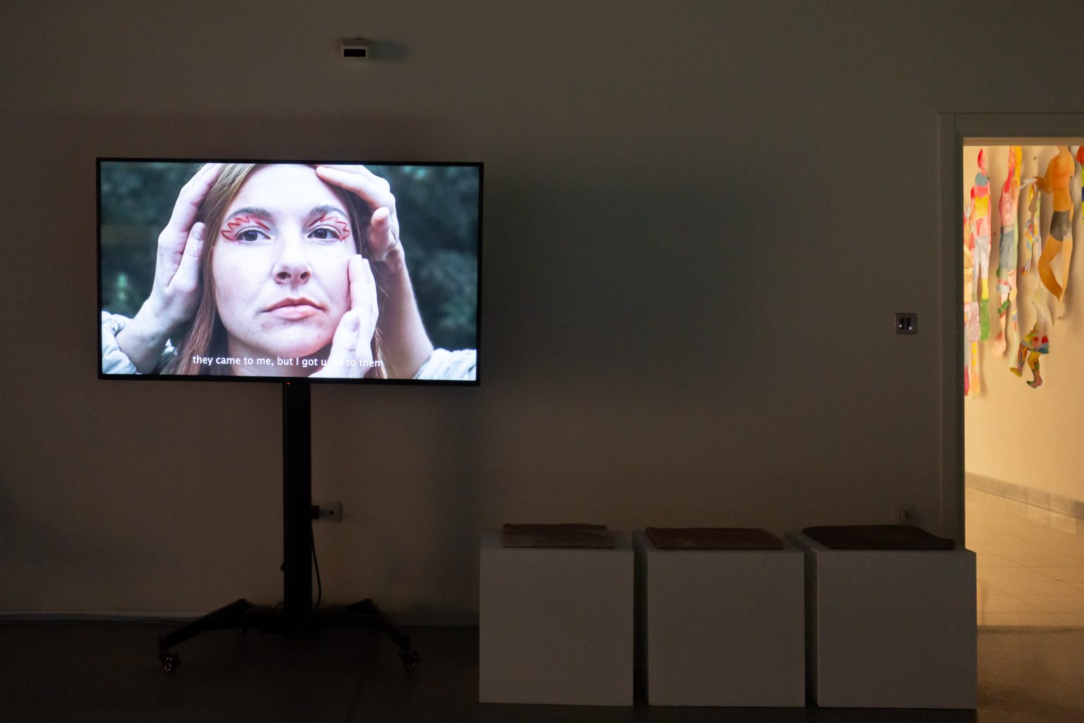 Monitor wyświetla głowę kobiety z przyłożonymi trzema dłońmi