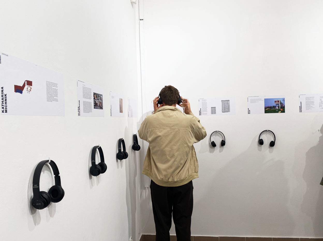 Stojących przy stanowiskach audio w sali wystawowej mężczyzna w słuchawkach