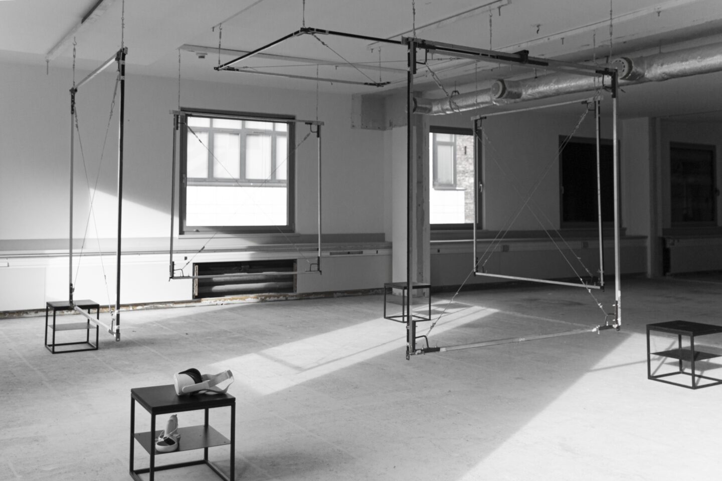 Obszar z zaaranżowaną scenografią VR - metalowe obiekty w formie ram, które nakreślają przestrzeń sześcianu, a w rogach stoliki z okularami do VR.