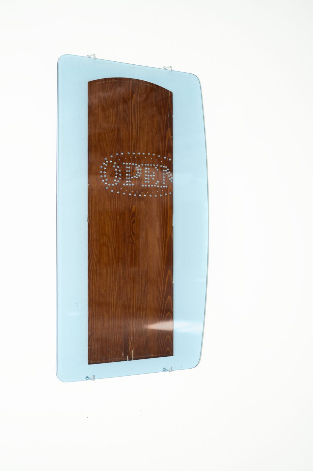 Drewniana deska z napisem „OPEN”, który wyklejony jest drobnymi diamentami. Całość oprawiona jest w lekko błękitne szkło.