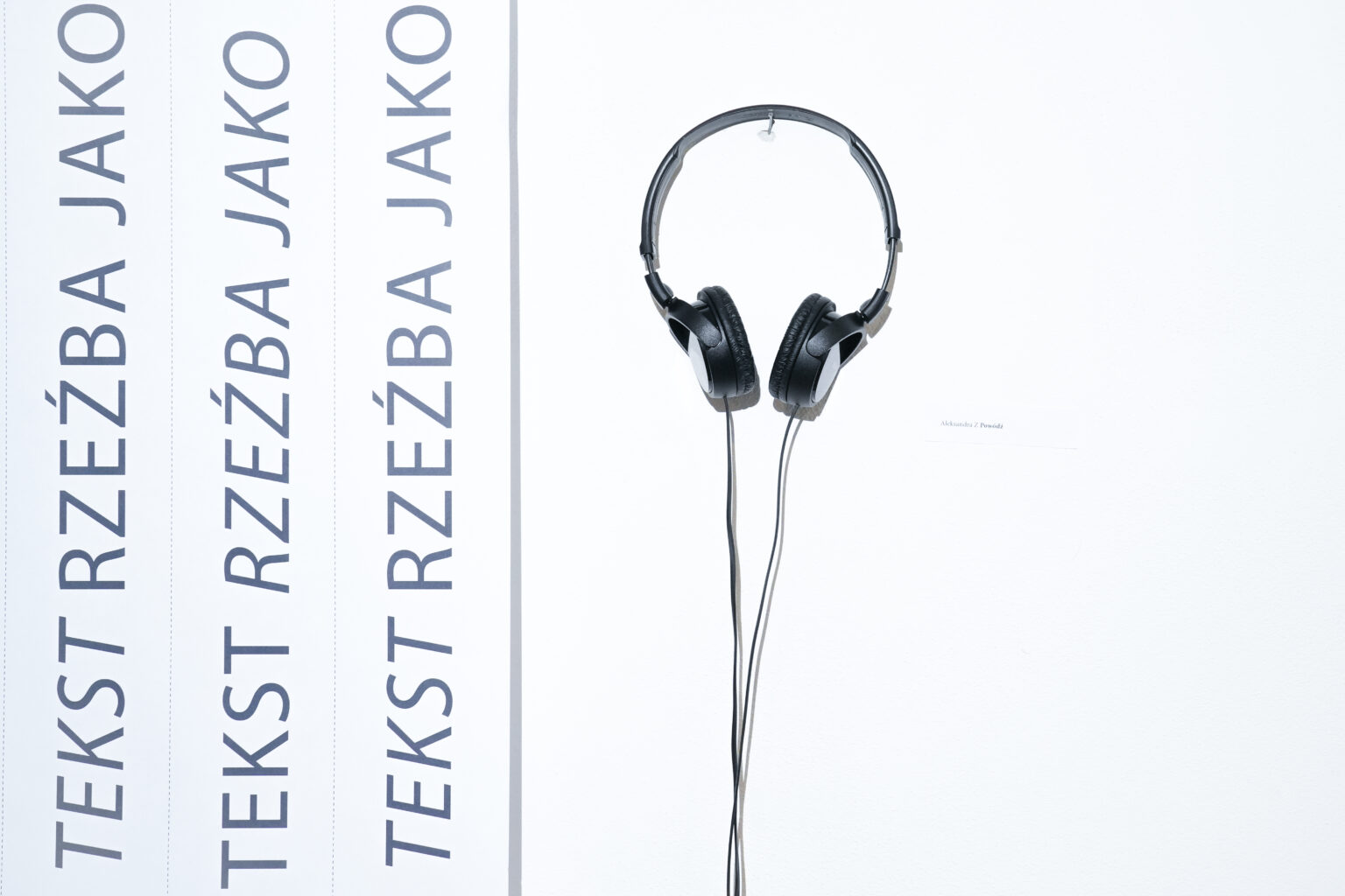 Fotografia przedstawia pracę dźwiękową – słuchawki, w których rozbrzmiewa utwór Aleksandry Z, podczas wystawy „Rzeźba jako tekst” w Muzeum Woli.