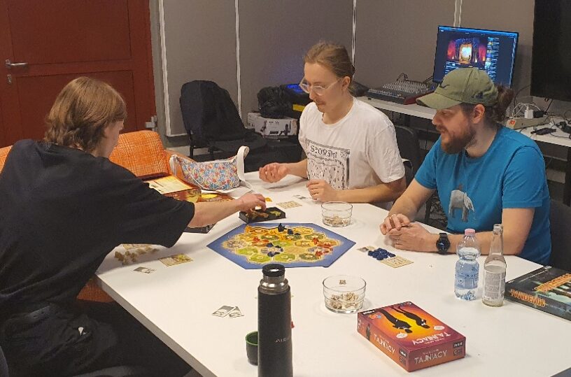 Grupa osób gra w grę planszową "Osadnicy z Catanu"