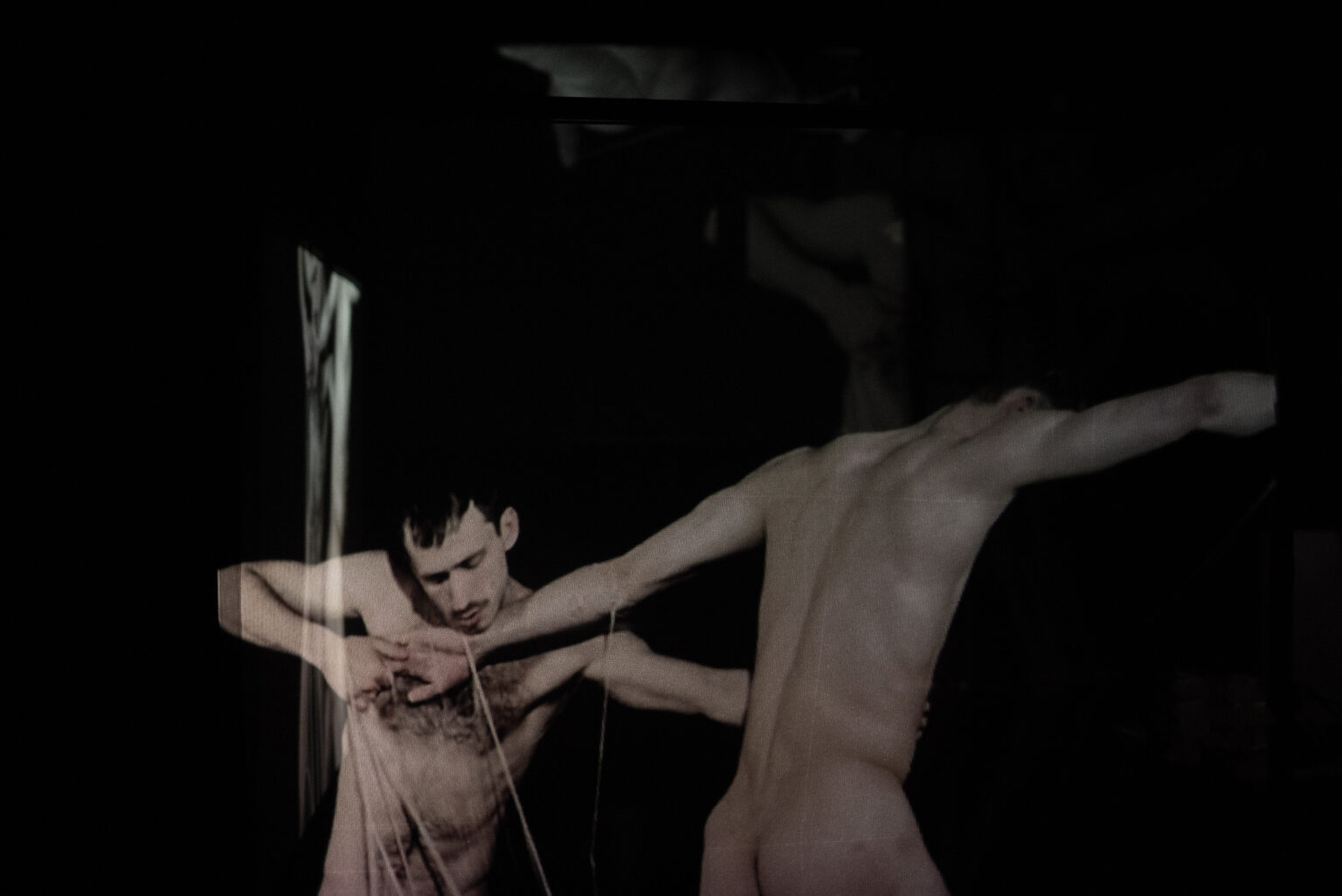 Wideo instalacja przestrzenna przestawiająca intymne relacje między dwojgiem mężczyzn. Projekcja na trzech transparentnych ekranach