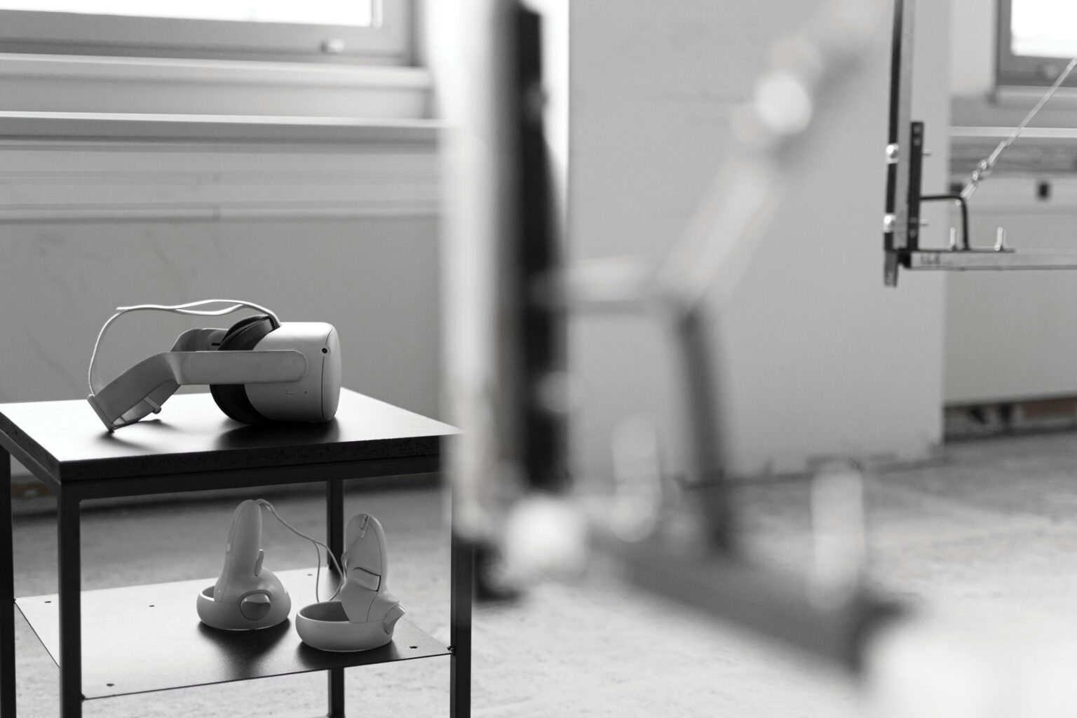 Metalowe obiekty przestrzenne eksponowane w Hop Gallery. Obszar z zaaranżowaną scenografią VR - metalowe, płaszczyzny w formie ram, które nakreślają przestrzeń sześcianu, a w rogach stoliki z okularami do VR.