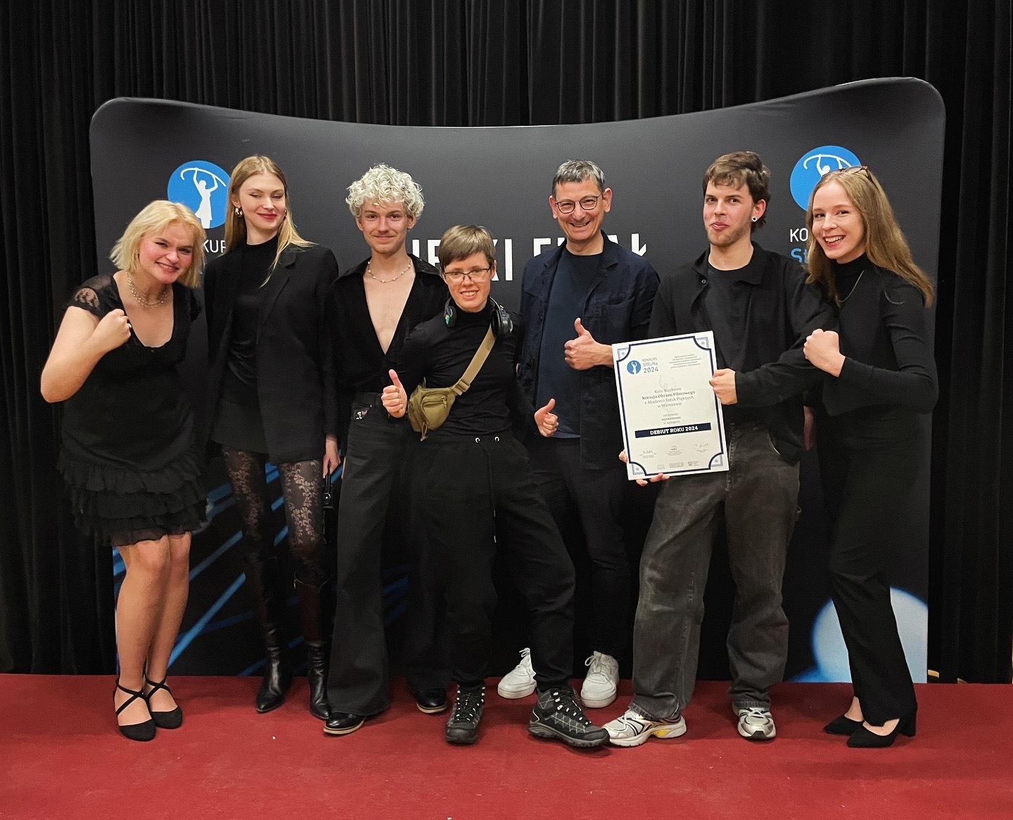 Członkowie i członkinie Koła Naukowego „Kreacja Obrazu Filmowego” z Wydziału Sztuki Mediów na ściance zdjęciowej na wydarzeniu StRuNa 2024.