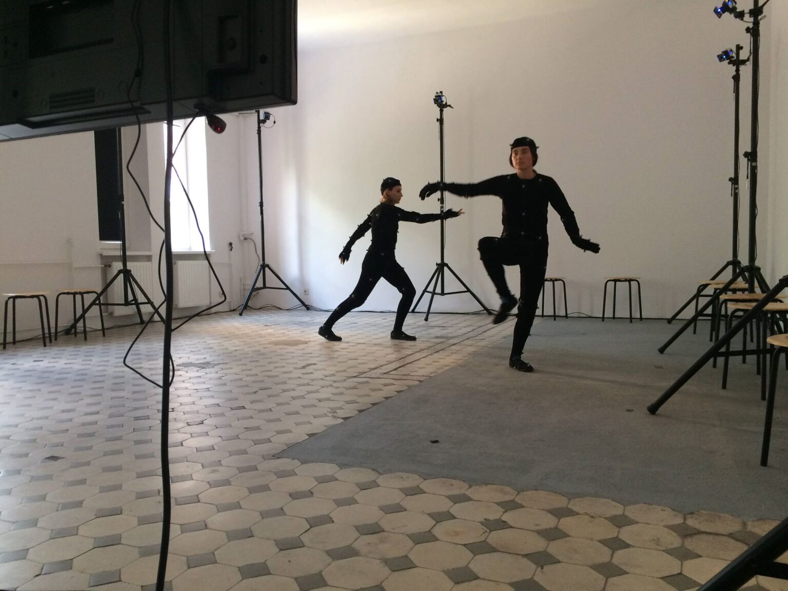 Dwie osoby wykonują choreografię w kostiumach do systemu motion capturte.