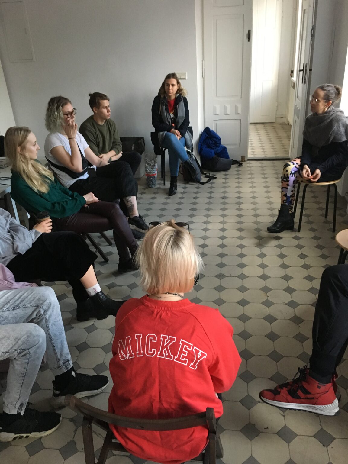 dyskutująca grupa osób siedzących na krzesłach w kole.