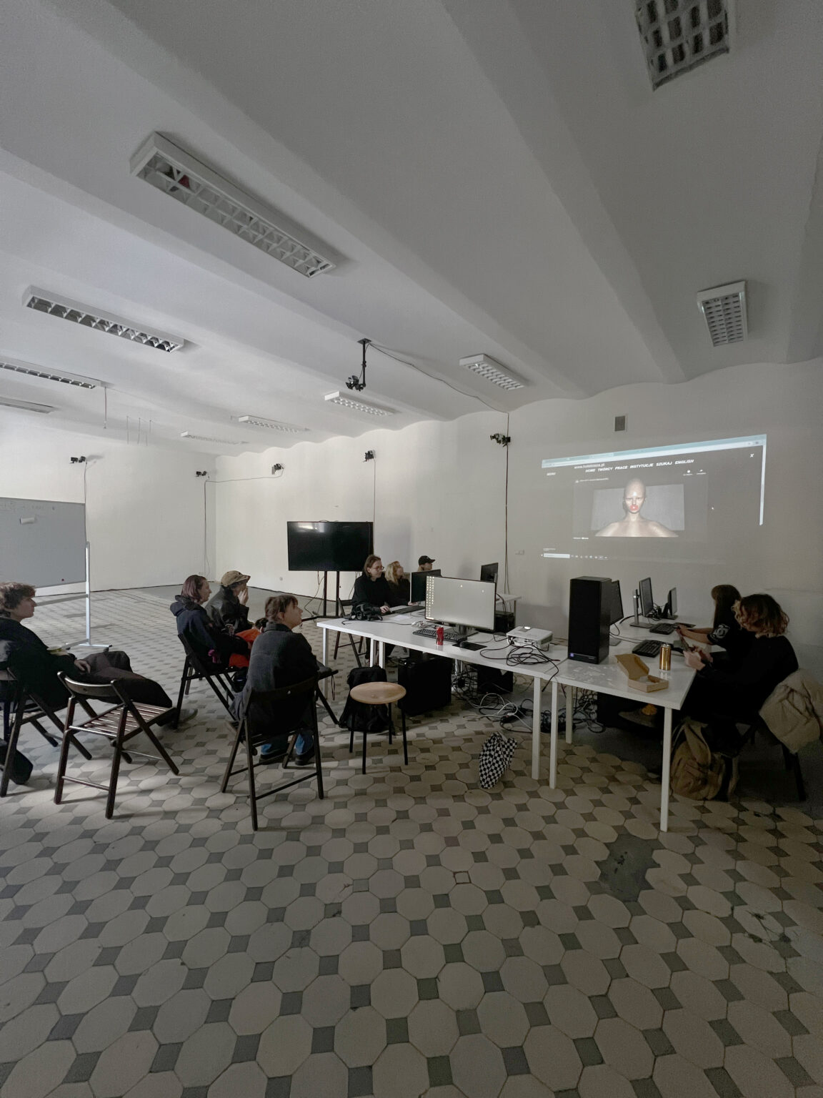 osoby przy stanowiskach komputerowych patrzą na projekcję przedstawiającą przykład pracy artystycznej.