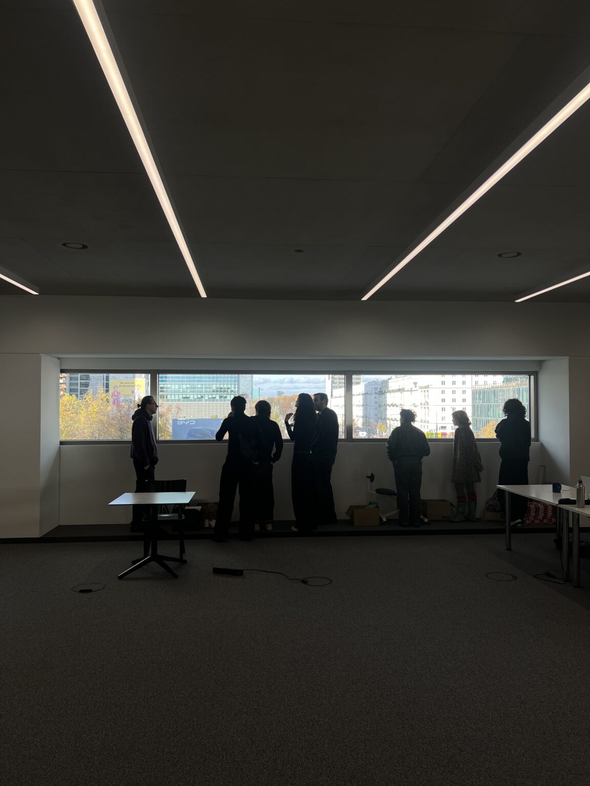 grupa osób stojąca przed poziomymi oknami w gmachu Muzeum Sztuki Nowoczesnej.