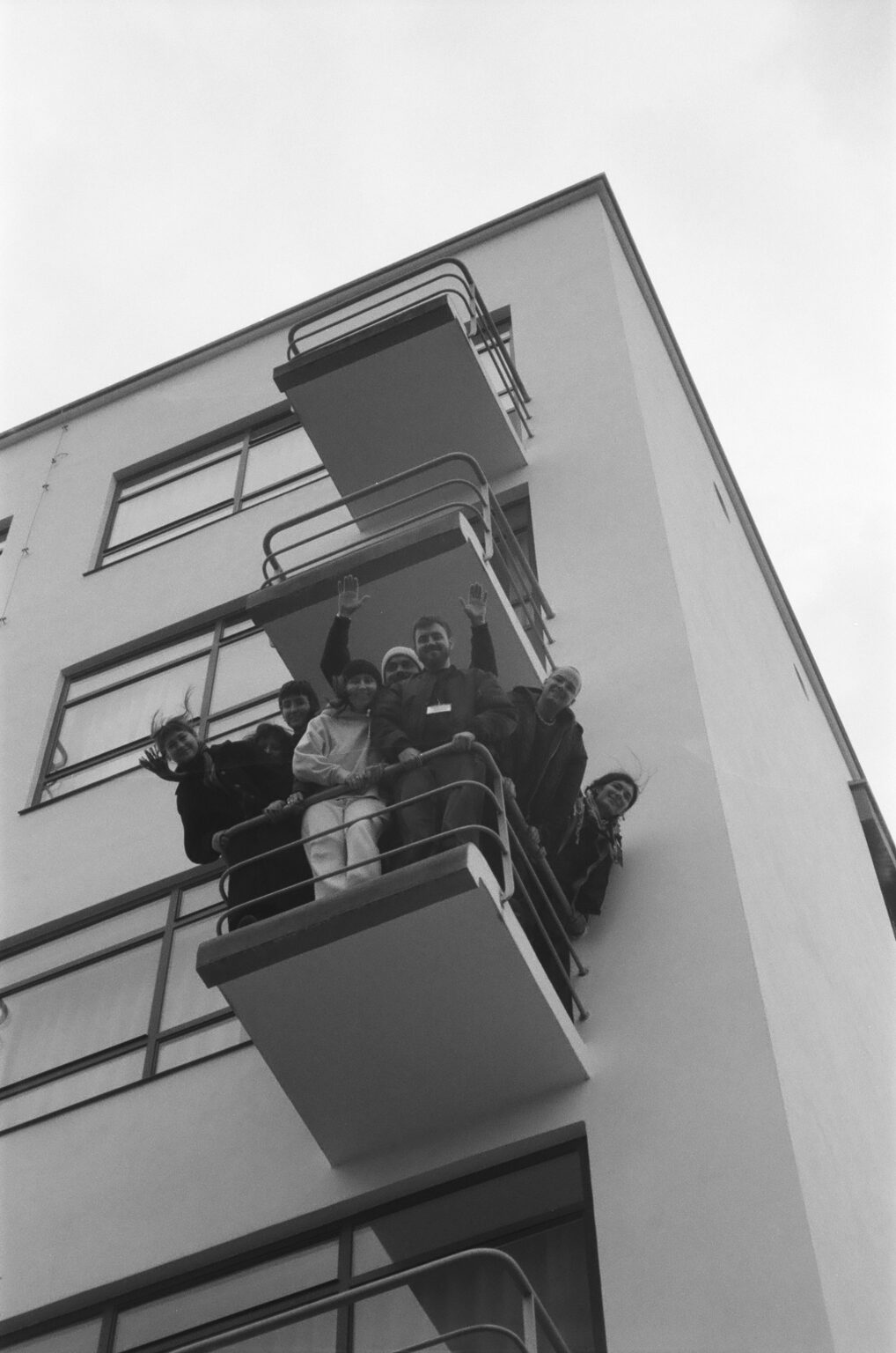 Zdjęcie grupy osób na balkonie historycznego budynku Bauhausu w Dessau
