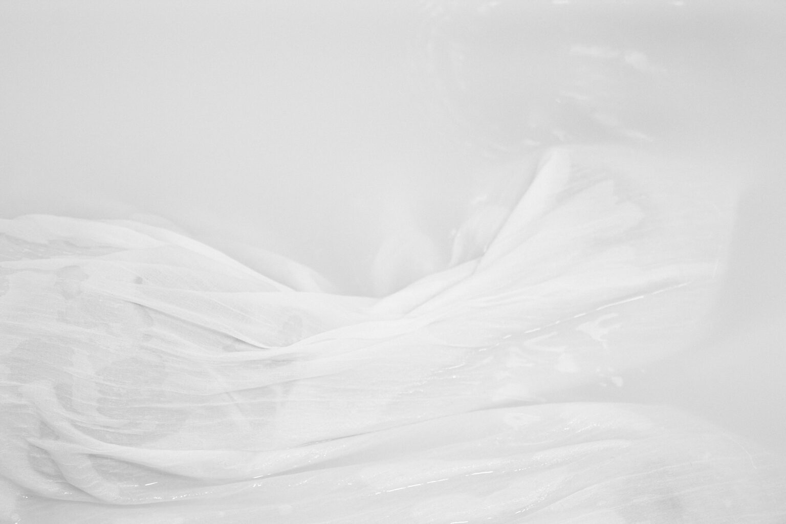 fragment białego materiału unoszącego się na powierzchni zabielonej wody.