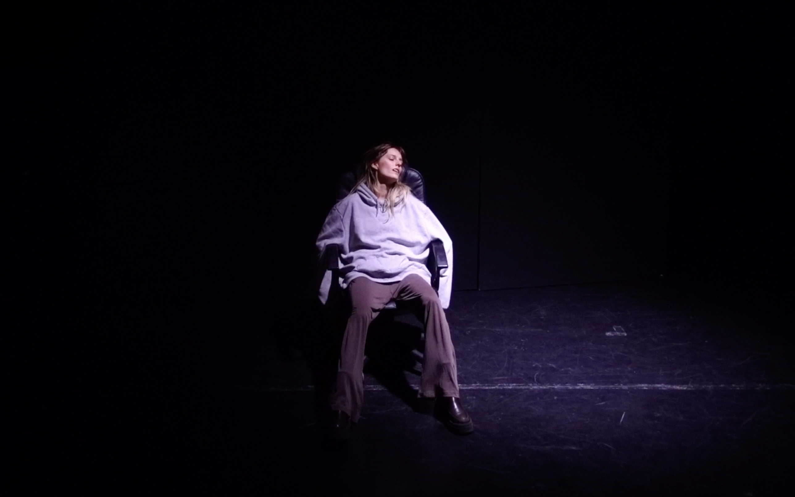 Na środku sceny z ciemności wyłania się dziewczyna siedząca na fotelu na kółkach. Jej ręce zwisają poza oparciami fotela. Dziewczyna ma zamknięte oczy i uchylone usta. Oświetlona jest słabym zimnym światłem kontrowobocznym z prawej strony sceny.