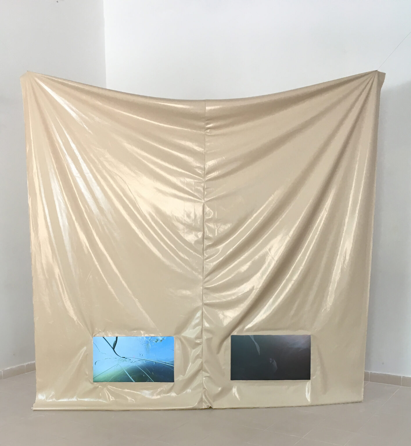 zawieszona lateksowa tkanina, na dole dwa otwory na 2 ekrany, na nich kadry z animacji 3D