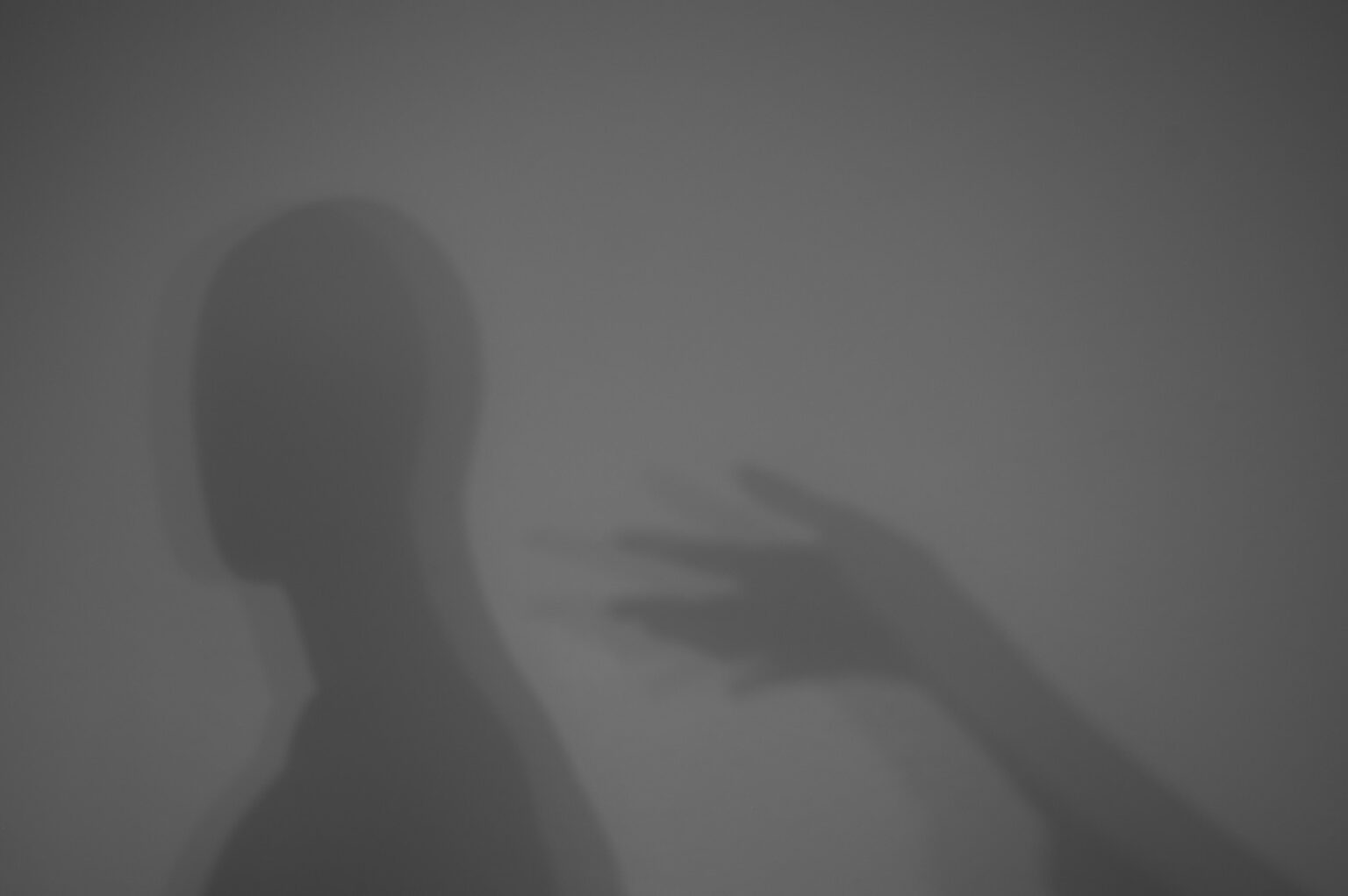 cień sylwetki manekina i ręki na jasnym tle.